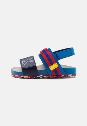 Infradito blu con una strap navy con logo, elastici a strisce rosse e blu e una suola decorata con un design ondulato.