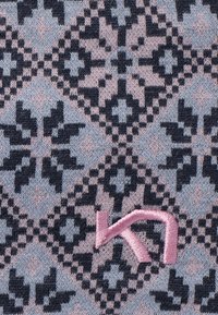 Gebreide stof met een geometrisch patroon in donkerblauw en lichtroze, met een geborduurd logo in roze. Zachte textuur, herhalende vormen.
