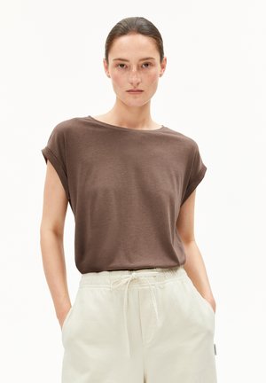 Brown short-sleeved t-shirt with rolled cuffs, made of a soft material. Paired with creamy white jogger pants featuring pockets.