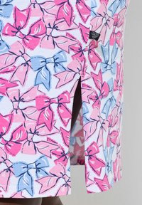 Bavlněná látka s pastelovou barevnou paletou obsahující růžové a modré mašle. Design zahrnuje detail s bočním rozparkem pro zvýšení stylu.