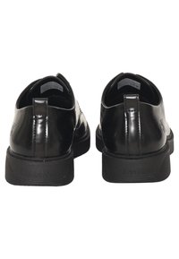 Scarpe in vernice nera con una finitura liscia, punta arrotondata e suola in gomma spessa. Presentano un'etichetta per il tallone e un accento con logo.