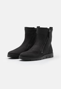 Botas negras hasta el tobillo, hechas de ante y cuero texturizado, con un cierre lateral y una suela de goma baja con ranuras para mayor tracción.