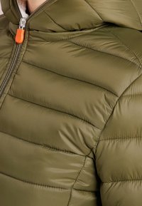 Grøn pufferjakke med vandret syninger, stoftekstur, frontlynlås med en klar orange trækstrop og hætte.