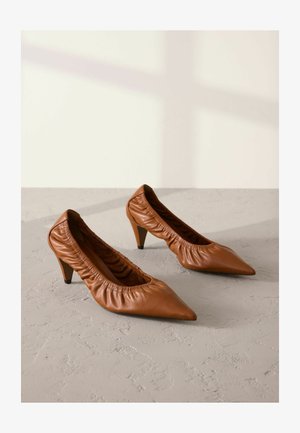 Ruske kožne visoke potpetice s dugim nosom, elastična gumica duž ruba i uska potpetica, postavljene na neutralnu pozadinu.