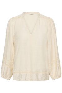 Blouse crème à manches longues avec col en V, bordure en dentelle aux épaules, manches et ourlet, et manches légèrement bouffantes avec poignets élastiques.