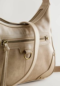 Borsa a spalla in pelle beige con una texture liscia, dotata di una tasca con zip dorata, un accentuato anello e dettagli cuciti. Inclusa tracolla regolabile.