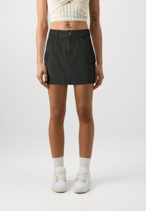 Dark green cargo skirt with two side pockets, straight cut, and button closure, made of durable fabric with a smooth texture.