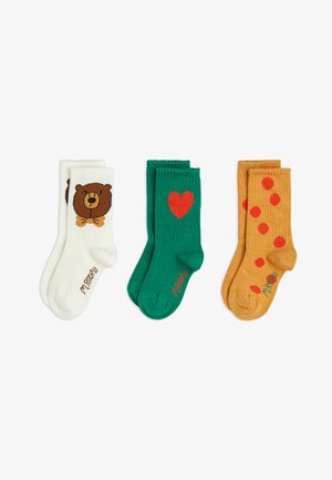 Drie paar kindersokken in wit met een beer, groen met een rood hart, en mosterdkleurig met rode stippen.