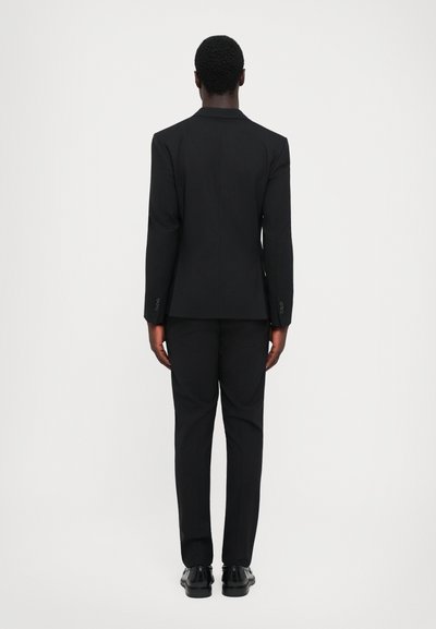 Schwarzer maßgeschneiderter Anzug mit einer enganliegenden Jacke und geraden Hosenbeinen. Glatte Textur, minimalistisches Design und klassische Knopfakzente.