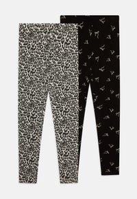 Deux paires de leggings : l'une avec un imprimé léopard noir et gris, l'autre unie noire avec des motifs de nœuds blancs. Les deux sont extensibles et ajustés.