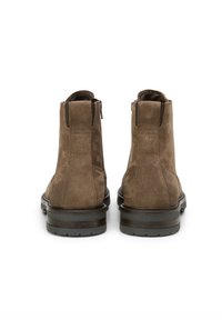 Brown suede ankle boots with a smooth texture, rubber soles, and zippered sides, featuring a logo detail on the heel.