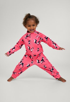 Rosa Jumpsuit mit vollem Reißverschluss, der mit schwarz-weißen Fuchs-Mustern verziert ist, aus weichem Stoff, mit langen Ärmeln und elastischen Bündchen. Ein Kind in einer spielerischen Pose.