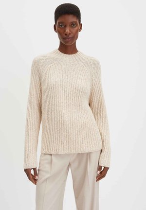 Kuscheliger beiger Strickpullover mit geripptem Muster, Rundhalsausschnitt und langen Ärmeln. Trägt man über hellen Hosen. Dezente schimmernde Details.