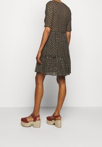 Musta kukkakuosiset mekko puffihelmoilla, kerroksilla varustetulla röyhelöhännällä ja istuvalla vyötäröllä. Yhdistettynä punaisiin korkokenkiin, joissa on kudottu pohja ja nilkkahihnat.