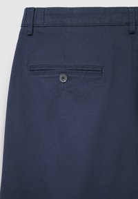 Navyblaue, strukturierte Stoffhose mit einer einzelnen Gesäßtasche mit schwarzem Vierlochknopfverschluss.