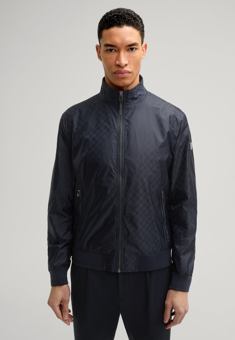 Marineblauer gefütterter Bomberjacke mit strukturiertem Muster, hohem Kragen und Fronttaschen. Aus leichtem, glattem Material gefertigt.