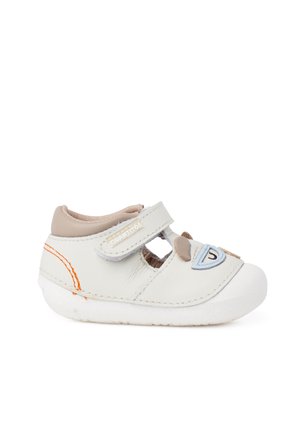 Chaussure blanche pour tout-petit avec bride velcro, accents beige, coutures orange et motif visage de chien sur le devant, affichée sur fond blanc.