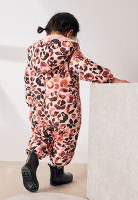 Gepolsterter Overall in Leopardenmuster in Pink, Braun und Schwarz; mit Kapuze und elastischen Bündchen; kombiniert mit schwarzen Gummi-Stiefeletten.