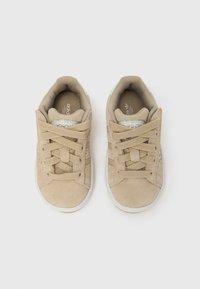 Μπεζ σουέντ αθλητικά παπούτσια με υφασμάτινα κορδόνια, λαστιχένια σόλα και λογότυπο με τρεις ρίγες. Διαθέτουν επένδυση με μαξιλαράκι και λεία φόδρα.