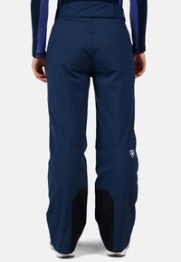 Marina vattentäta skidbyxor med hög midja, förstärkta svarta ben och logodetalj på låret. Slät textilstruktur.
