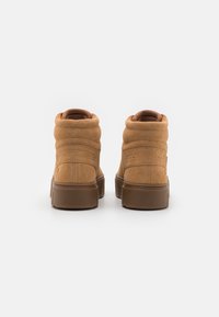 Baskets hautes en suede marron avec un col rembourré, des accents cousus et une semelle en caoutchouc épaisse. Vue arrière mettant en avant la texture et le design.
