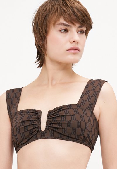 Brown bikini top with a ruched front, wide shoulder straps, and a cutout detail. Features a repeating black logo pattern. Smooth texture.