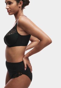 Schwarzes Dessous-Set mit einem Spitzenbesatz-BH mit Punkten und hochgeschnittenen Panties mit Spitzenakzenten, beide aus dehnbarem Stoff.