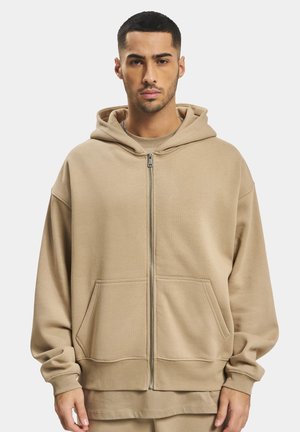 Beige Kapuzenpullover mit Reißverschluss, aus weichem Material gefertigt, mit einer geräumigen Kapuze, Fronttaschen und einer lockeren Passform. Einfaches Design mit gerippten Bündchen.