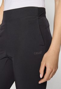 Svarta träningsleggings av stretchmaterial med hög midja, sidficka och präglad logga på nederbenet.