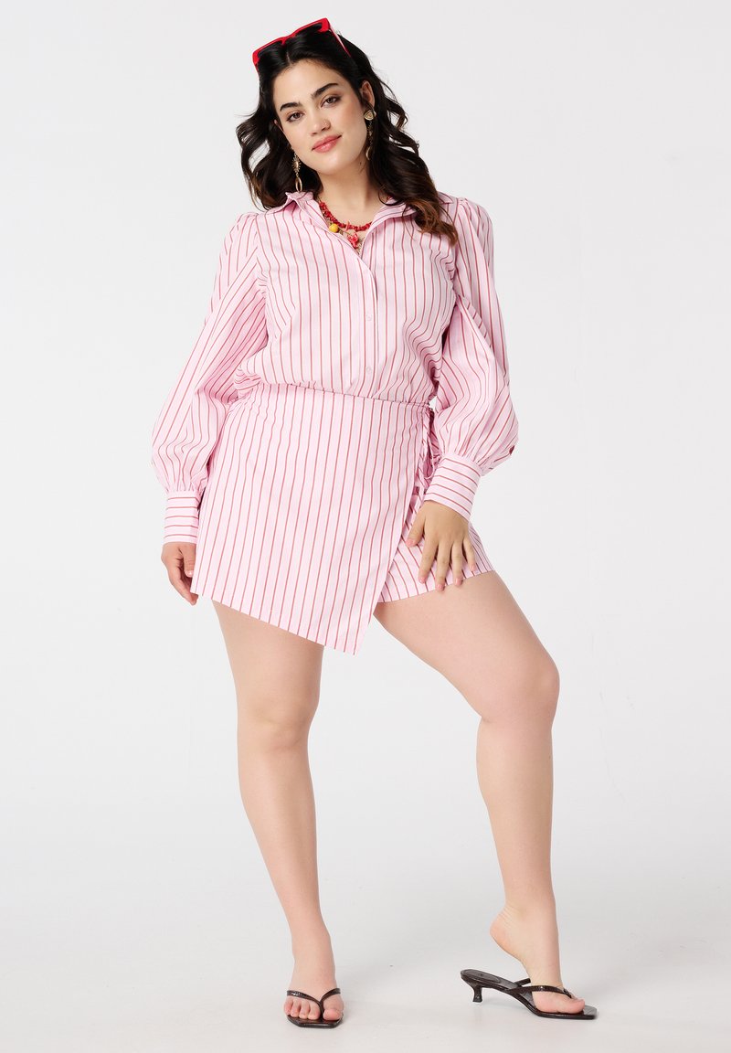 Chemise rayée rose à manches bouffantes longues, associée à une jupe asymétrique assortie. Présente un col et une texture de tissu lisse.