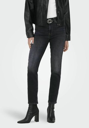 Black denim jeans with a slim fit, featuring a dark wash, subtle fading, and a metal belt buckle. Paired with black heeled ankle boots.