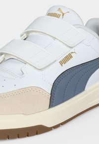 Λευκό sneaker Puma με μπεζ μύτη, μπλε πλευρική ρίγα, χρυσό λογότυπο Puma και δύο λευκές λουρίδες βέλκρο.