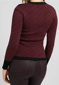 Pull bordeaux à motifs losanges, bordures noires aux poignets et à l'ourlet, coupe ajustée, texture tricotée, porté avec un pantalon foncé.