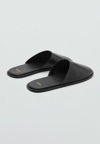 Infradito neri realizzati in pelle liscia, con design aperto sulla punta e suola piatta. Accento con logo dorato sulla soletta.