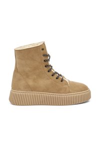 Botines de ante en color arena con suela de goma gruesa y estriada. Cuentan con cordones en blanco y negro y un forro de forro polar suave.