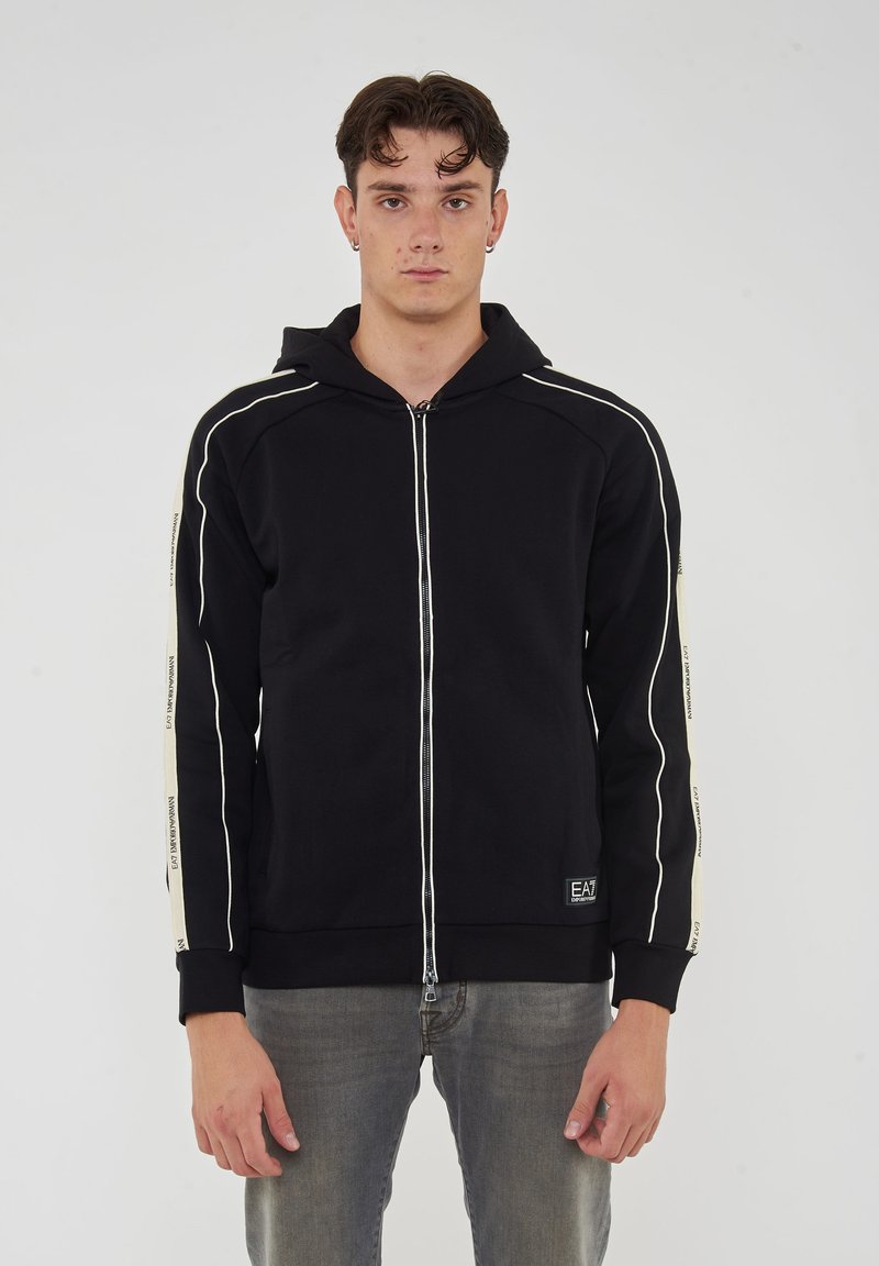 Felpa con zip nera con strisce bianche sui maniche, polsini a costine e cappuccio, realizzata in morbido cotone.