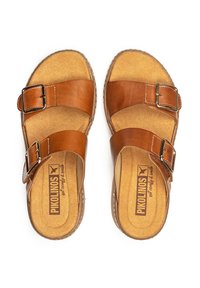 Sandalias de cuero marrón con dos hebillas ajustables, plantilla de corcho y forro textil en tono marrón. Punta redonda y suela plana. Nombre de la marca visible en el interior.
