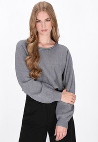 Pulover gri scurt cu un decolteu rotund, mâneci largi și manșete cu nervuri, asortat cu pantaloni negri. Textură netedă și croială lejeră.