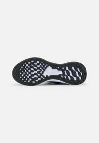 Suola di scarpa atletica in bianco e nero con un design in gomma testurizzata, caratterizzata da scanalature e motivi vari per migliorare la trazione e la flessibilità.