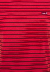 Camiseta de rayas rojas hecha de una tela suave, con rayas horizontales de un rojo oscuro y un pequeño logo de Levi's en la esquina superior izquierda.