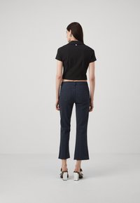 Zwart cropped polo-shirt met korte mouwen, gecombineerd met marineblauwe gestreepte flared broeken en witte blokhak sandalen.