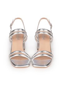 Silberne High-Heel Sandalen mit offenem Zehenbereich, ausgestattet mit gekreuzten Riemen und einer Schnallenverschluss. Strukturierte Metalloberfläche. Flacher Absatz.