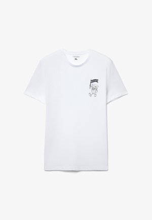 Biała bawełniana koszulka z małą czarną postacią z kreskówki trzymającą flagę na lewej piersi. Okrągły dekolt i krótki rękaw.