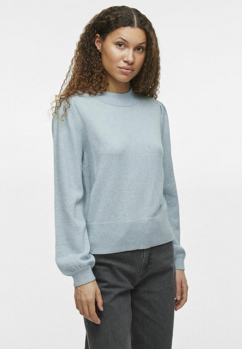 Pull bleu clair en matériau doux, avec un col et des poignets côtelés, une taille ajustée et une coupe décontractée.