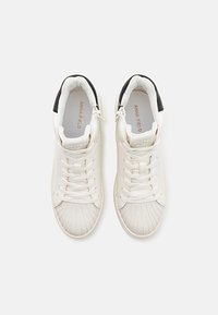 Białe sneakersy typu high-top z teksturowanymi detalami, gładką skórzaną cholewką oraz czarnymi akcentami na pięcie. Posiadają sznurowadła i boczny zamek.