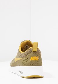 Nike tenisky v olivově zelené barvě s vrchním materiálem z mesh, s žlutými akcenty a perorovanými detaily. Mají bílou mezipodešev a polstrovaný límec.