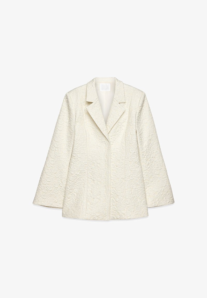 Hvid tekstureret blazer med et struktureret design, der har en spids krave og lange ærmer, lavet af et mønstret stof.