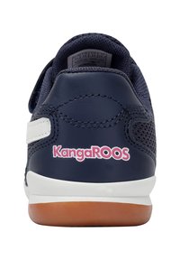 Marineblauer Sneaker mit einem Obermaterial aus Mesh, ausgestattet mit einem Klettverschluss, weißen Akzenten und einer Gummisohle in Karamellfarbe. "KangaROOS"-Logo in Pink an der Ferse.