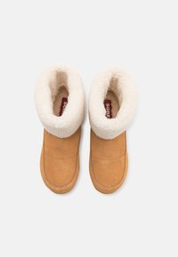 Stivali alla caviglia suede color sabbia con fodera e colletto in pelliccia sintetica color crema; progettati con dettagli cuciti e una suola resistente.
