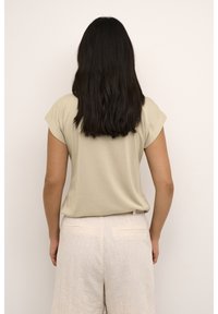 Lichtbeige shirt met korte mouwen, een relaxte pasvorm, een gestructureerde stof en een ronde zoom, gecombineerd met lichte linnen broek met subtiele achterzakken.